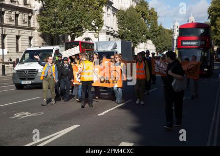 Gli attivisti “Just Stop Oil” cercano di tenere uno striscione davanti al traffico di Westminster, nel centro di Londra. Foto Stock