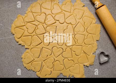 Taglierine per biscotti a forma di cuore che tagliano le vacanze. Come tagliare i biscotti a forma di cuore dall'impasto. Cucinare una deliziosa e salutare colazione di vacanza naturale Foto Stock