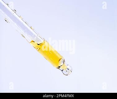 Foto macro di olio cosmetico o essenziale, siero che cade dal contagocce di vetro Foto Stock