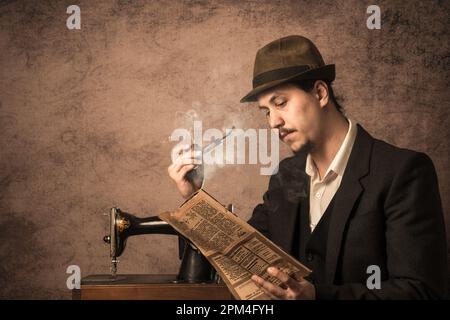 Un uomo fuma una pipa e legge un giornale. Stile retrò. Foto Stock