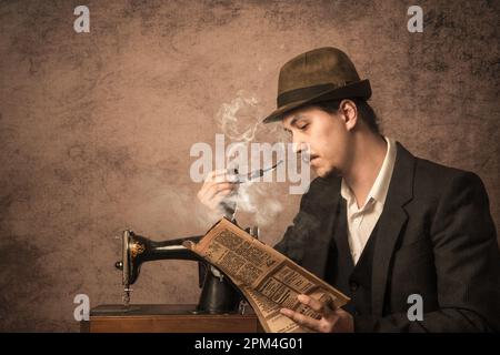 Un uomo fuma una pipa e legge un giornale. Stile retrò. Foto Stock