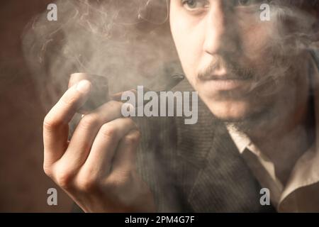 Un uomo fuma una pipa e legge un giornale. Stile retrò. Foto Stock