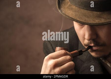 Un uomo fuma una pipa e legge un giornale. Stile retrò. Foto Stock