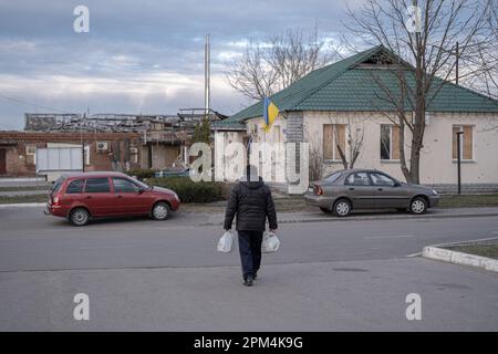 Un uomo visto dopo aver ricevuto aiuti umanitari nel villaggio di Tsyrkuny. L'area di Kharkiv e la parte settentrionale della città hanno sofferto pesantemente durante l'invasione russa. Il primo giorno della guerra, le truppe russe occuparono i villaggi circostanti, sorpresendo gli abitanti e non dando loro alcuna possibilità di fuggire. L'occupazione durò 2,5 mesi, durante i quali molti residenti furono uccisi e gli edifici e le infrastrutture distrutte. Nonostante quasi un anno dalla sua fine, la zona rimane pericolosa a causa della sua vicinanza alla Russia. I sopravvissuti spesso vivono in case parzialmente rovinate senza servizi di base. Loro ali Foto Stock