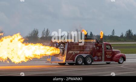 Un camion dei pompieri con una scala alta e un grande modello di fiamma in cima è parcheggiato in un aeroporto Foto Stock