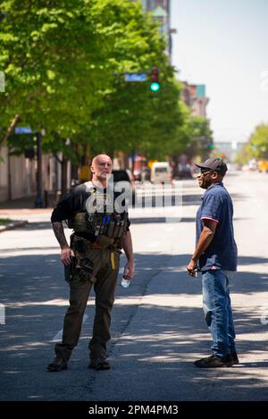 Louisville, Kentucky, Stati Uniti. 10th aprile 2023. L'ufficiale della polizia della metropolitana di Louisville parla con un osservatore fuori dalla scena delle sparatorie di massa a Old nati Foto Stock