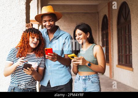 Un gruppo di giovani che utilizzano gli smartphone per guardare i social media all'aperto. Foto Stock