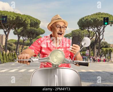 Turista maschile maturo in sella a uno scooter e guardando uno smartphone nella capitale di Roma, Italia Foto Stock