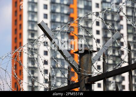 Filo spinato sul fondo dell'edificio residenziale. Concetto di guerra e sicurezza in città Foto Stock