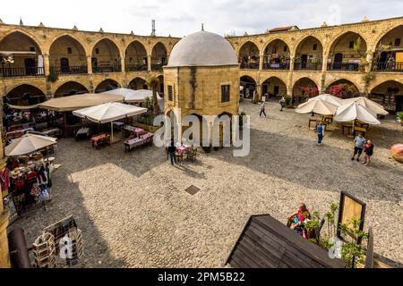 Cortile interno Büyük Han, Great Inn, il più grande caravanserai di Cipro. Costruito per ordine del primo sovrano degli Ottomani a Cipro, Muzaffer Pasha, nel 1572. Nel cortile si trova una piccola moschea con tetto a cupola e una fontana per le abluzioni prima della preghiera. L'edificio è considerato uno degli edifici più belli di Cipro e si trova nella parte nord cipriota della città divisa di Nicosia, Cipro Foto Stock