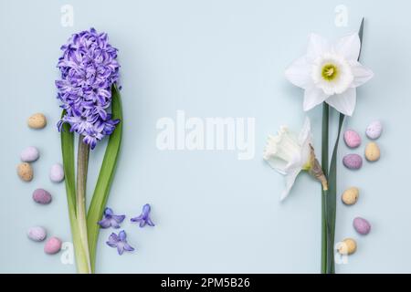 Un Hyacinto e Daffodils con uova di pasqua sparse su sfondo blu pastello primavera ancora vita Foto Stock