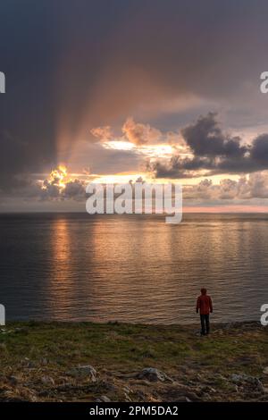 Uomo in piedi che guarda l'alba su montagne di mare Foto Stock