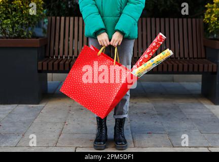 donna che tiene una borsa con regali e carta da imballaggio prima delle feste Foto Stock