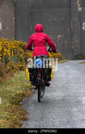 Donna che viaggia su una bicicletta carica di borse Foto Stock