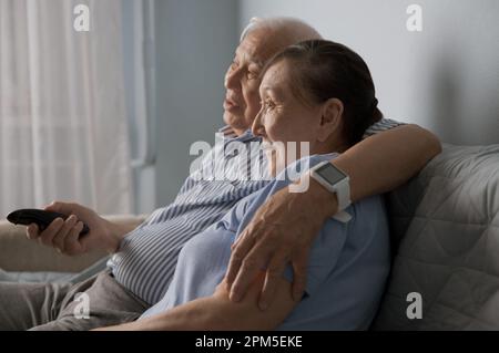 Coppia senior che guarda la tv e usa il telecomando a casa Foto Stock