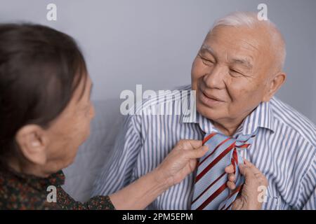 Donna anziana che lega la cravatta del marito Foto Stock