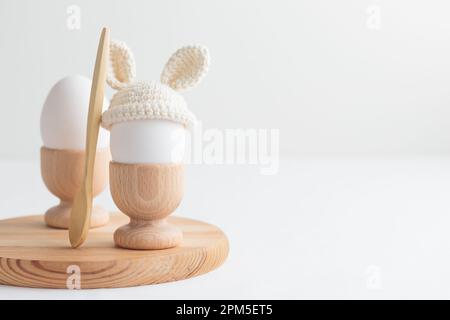 uovo di pasqua in cappello all'uncinetto con orecchie da coniglio in portuovo di legno Foto Stock