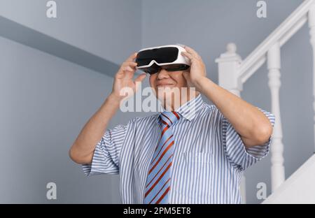 Uomo anziano che ha esperienza di realtà virtuale con il dispositivo visore VR Foto Stock