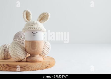 uovo di pasqua in cappello all'uncinetto con orecchie da coniglio in portuovo di legno Foto Stock