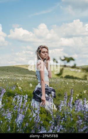 ragazza attraente sul campo con fiori bianchi e lilla Foto Stock