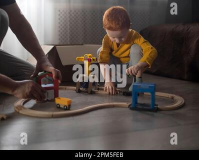 Papà e bambino stanno costruendo una pista di legno per i treni. Foto Stock