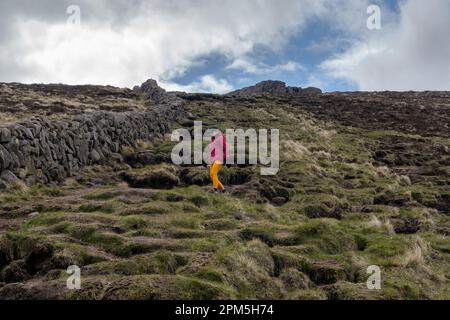 Donna escursionista che scende dalla cima del monte PF Foto Stock