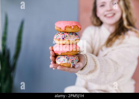 Donna felice sorridendo e tenendo in mano una pila di ciambelle Foto Stock
