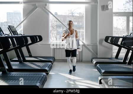Muscolo maschio bodybuilder che ha la rottura dopo cardio sulla macchina del tapis roulant Foto Stock