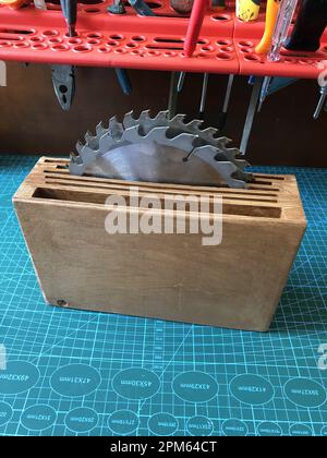 seghe circolari in acciaio in una scatola di legno su un tavolo in officina Foto Stock