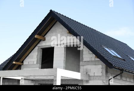 Casa incompiuta con tetto nero contro il cielo blu Foto Stock