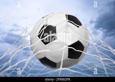Palla di calcio in rete contro cielo nuvoloso Foto Stock