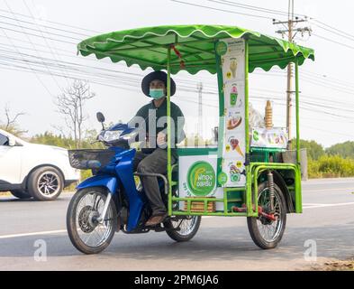 BANGKOK, THAILANDIA, MAR 11 2023, un fornitore di gelati guida una moto a tre ruote lungo una strada del villaggio Foto Stock