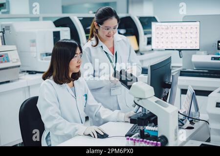 Un team di scienziati della ricerca medica che lavorano collettivamente su nuove conoscenze di ricerca delle scienze con il microscopio in laboratorio. Tecnologia medica. Foto Stock