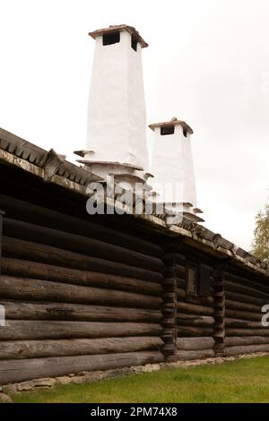 Parete di legno e due pile di camino dipinte di bianco. Foto Stock