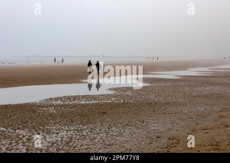 I visitatori di Camber Sands camminano sulla spiaggia in una misticissima Domenica di Pasqua mattina. Foto Stock
