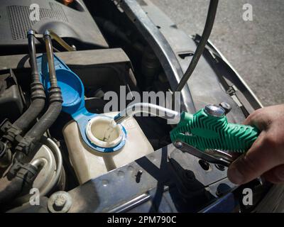 Riempimento dell'acqua nel serbatoio del lavacristallo. Riempito con acqua direttamente con un tubo flessibile Foto Stock