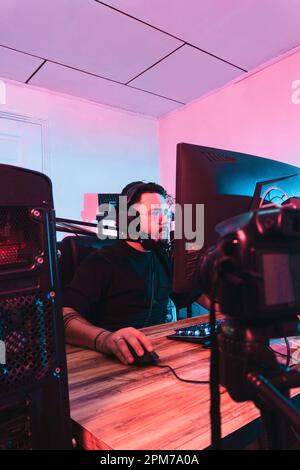 Uno scatto verticale di uno streamer maschio che gioca ai videogiochi sul suo monitor Foto Stock