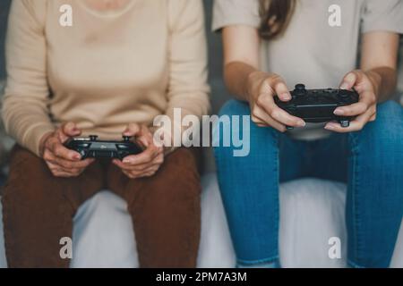 Due donne che hanno controller di gioco nero per la xbox, giocare console per videogiochi. Concetto di stile di vita della gente. Concetto di attività familiare. Concetto di hobby. Foto Stock
