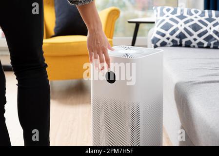Donna che usa purificatore d'aria, aria fresca a casa Foto Stock
