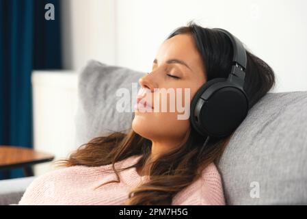 Donna con cuffie rilassanti, ascoltando musica, concetto chillout Foto Stock