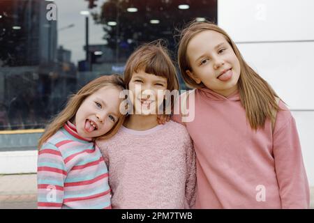 Carino felice divertente bambini ragazze grimacing, ritratto. Bambini che mettono fuori la lingua Foto Stock