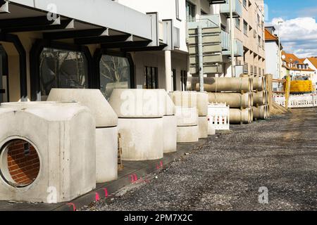 Strutture edili in cemento e stoccaggio di tubi sul marciapiede in cantiere. Foto Stock