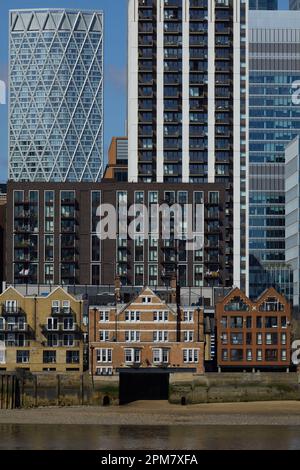 I grattacieli di Canary Wharf, parte del quartiere centrale degli affari di Londra, dominano in primo piano le vecchie abitazioni lungo il fiume Tamigi. Foto Stock