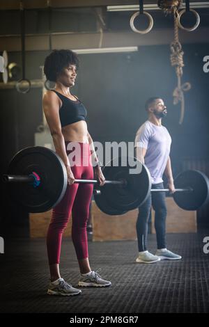 Giovane e donna biracial dedicato sollevamento di barbells mentre in piedi in palestra, spazio copia Foto Stock