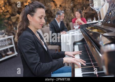 bella giovane donna che suona il pianoforte in un ristorante Foto Stock