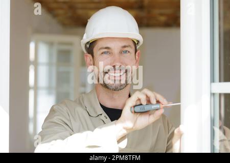 l'uomo costruisce un cacciavite nella parete di legno Foto Stock