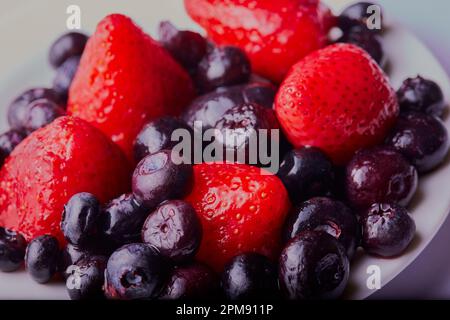 Ciotola di frutta mista, tra cui fragole, mirtilli, tutto da vicino e fresco. Foto Stock