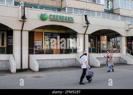 I pedoni passano davanti a un ramo di Sberbank della Russia sulla Komendantsky Prospekt, a San Pietroburgo. In precedenza, il 6 aprile 2022, Sberbank era sulla lista SDN con il blocco delle sanzioni statunitensi. Foto Stock