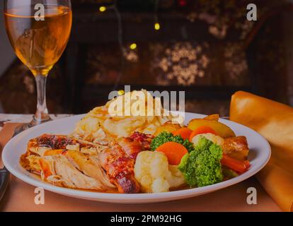 Cena di pollo di Natale, tacchino con un bicchiere di vino con luci sullo sfondo. Foto Stock