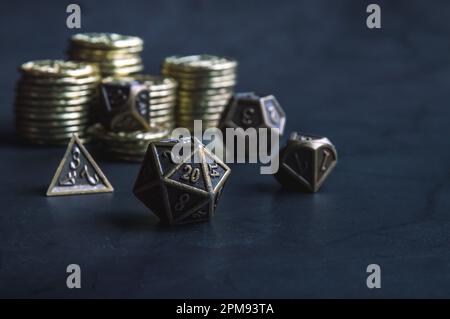 Immagine ravvicinata di un set di dadi RPG metallici e monete d'oro Foto Stock